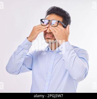 Uomo in studio con occhiali, strofinando gli occhi per la visione, la vista e stanco su isolato su sfondo bianco con burnout. Fatica, stress ed esausto Foto Stock