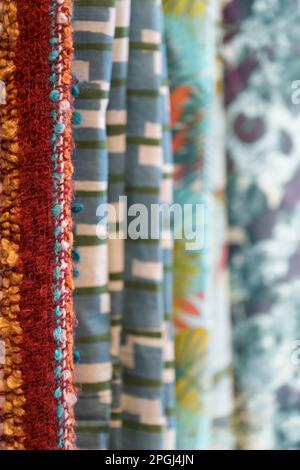 Tessuti tessuti con diversi motivi colorati appesi per la vendita in una fila, spazio copia, fuoco selezionato, profondità di campo molto stretta Foto Stock