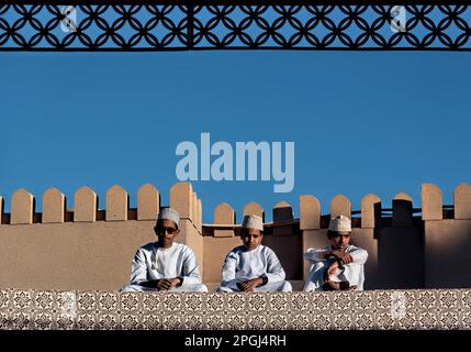 Ragazzi in abito tradizionale sul tetto del mercato di capra, Nizwa, Oman Foto Stock