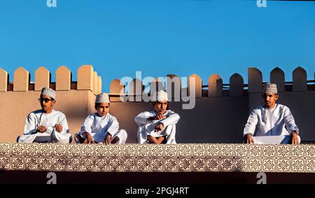 Ragazzi in abito tradizionale sul tetto del mercato di capra, Nizwa, Oman Foto Stock