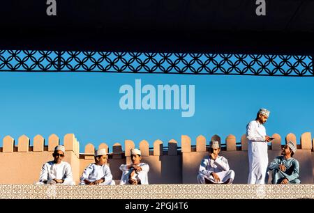 Ragazzi in abito tradizionale sul tetto del mercato di capra, Nizwa, Oman Foto Stock