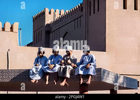 Ragazzi in abito tradizionale sul tetto del mercato di capra, Nizwa, Oman Foto Stock