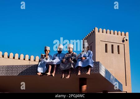 Ragazzi in abito tradizionale sul tetto del mercato di capra, Nizwa, Oman Foto Stock