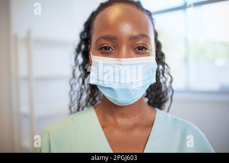 Primo piano ritratto di medico o infermiere junior indossare maschera chirurgica in scrub Foto Stock