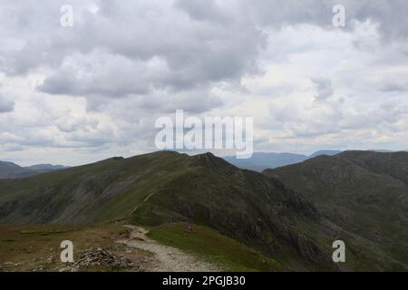 Una montagna isolata è visibile attraverso l'atmosfera nuvolosa, con lontane catene montuose sullo sfondo Foto Stock