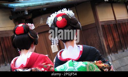 Due donne giapponesi che indossano kimono tradizionale e trucco ornato mentre camminano lungo una strada cittadina Foto Stock