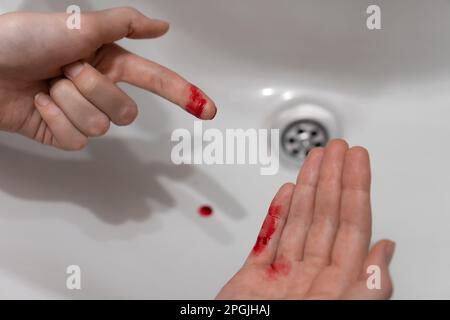 Primo piano del dito tagliato di una donna nel sangue sopra il lavandino Foto Stock