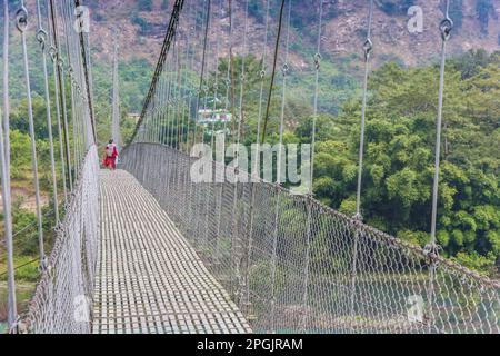 Le donne che attraversano la sospensione ponte sopra il fiume Trishuli in Nepal Foto Stock