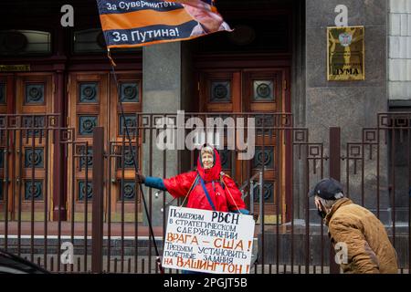 Mosca, Russia. 21st Mar, 2023. Un sostenitore del presidente Russiaís Vladimir Putin sventola una bandiera con un ritratto di Putin e un testo che recita: ìFor Motherland! Per la sovranità! Per Putin!î mentre tiene un cartello che recita: 'Sostegno alle forze strategiche Rocket della Federazione Russa nel loro sforzo di deterrenza strategica del nemico ó Stati Uniti Chiediamo assegnazioni di volo a Washington!' Vicino alla Duma di Stato a Mosca. (Foto di Vlad Karkov/SOPA Images/Sipa USA) Credit: Sipa USA/Alamy Live News Foto Stock