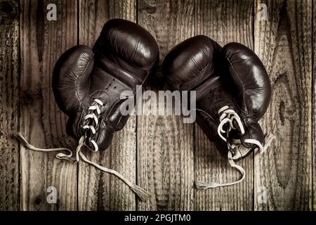 vecchi guanti da boxe su sfondo di legno Foto Stock