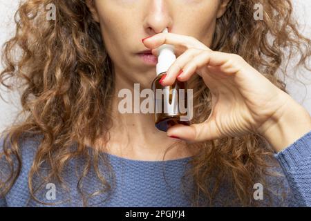 Donna malata con una rinite. Prendere gocce di naso a causa di allergia ai pollini. La donna sta avendo l'influenza e sta usando lo spray nasale per aiutare se stessa. Donna Foto Stock