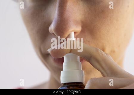 Donna malata con una rinite. Prendere gocce di naso a causa di allergia ai pollini. La donna sta avendo l'influenza e sta usando lo spray nasale per aiutare se stessa. Donna Foto Stock