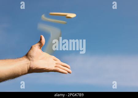 Uomo che lancia boomerang contro il cielo blu, primo piano Foto Stock