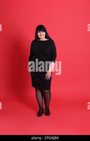Bella donna sovrappeso in abito nero su sfondo rosso Foto Stock