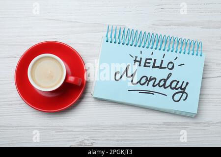 Messaggio Ciao Lunedi scritto in notebook e tazza di caffè su scrivania di legno bianco, piatto Foto Stock