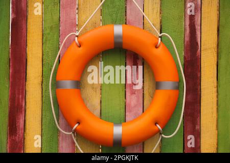 Salvagente arancione appeso a una recinzione di legno colorata. Attrezzatura di salvataggio Foto Stock
