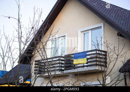 Casa ricostruita dopo l'attacco russo, Gostomel, Ucraina. Bandiera Ucraina sulla facciata dell'edificio. Primavera in Ucraina. Concetto di patriottismo. Bandiera dell'Ucraina Foto Stock