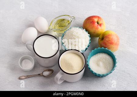 Ingredienti per torta di cocco, mannik: Semola o manka, yogurt, fiocchi di cocco, uova, olio vegetale, mele, zucchero, uova, lievito in polvere, sale su a li Foto Stock