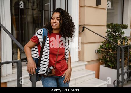Giovane donna nera sorridente mentre si è in piedi per costruire all'aperto Foto Stock