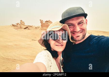 Coppia multirazziale che prende selfie nel deserto fossile ad Abu Dhabi, Emirati Arabi Uniti. Fun Time Together concetto di moda alternativa viaggiatori, multi-etnico ragazzo a Foto Stock