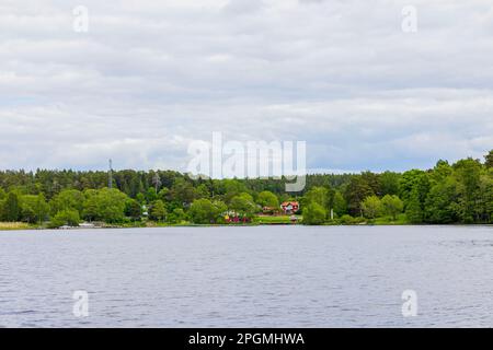 Splendida vista sul grande lago e sulle ville sulla riva opposta sullo sfondo della foresta. Svezia. Foto Stock