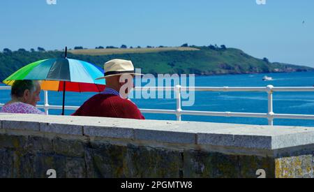 Plymouth, Devon, 06 luglio 2022; immagini dei giorni felici in pensione. Una coppia anziana ben vestita gode del sole e della vista dell'oceano. Foto Stock