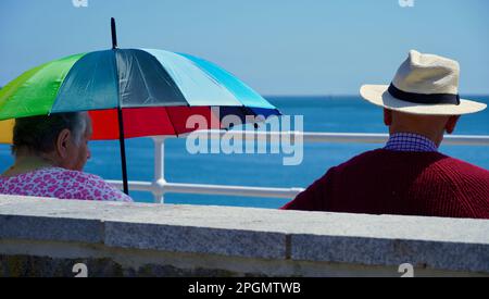 Plymouth, Devon, 06 luglio 2022; immagini dei giorni felici in pensione. Una coppia anziana ben vestita gode del sole e della vista dell'oceano. Foto Stock