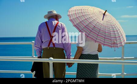 Plymouth, Devon, 06 luglio 2022; immagini dei giorni felici in pensione. Una coppia anziana ben vestita gode del sole e della vista dell'oceano. Foto Stock