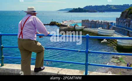 Plymouth, Devon, 06 luglio 2022; immagini dei giorni felici in pensione. Una coppia anziana ben vestita gode del sole e della vista dell'oceano. Foto Stock