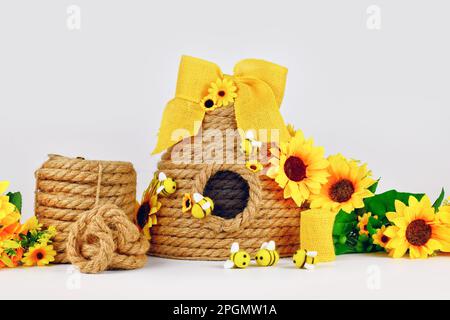 Decorazioni fai da te con alveare in corda con materiali come fiori falsi, corda in iuta e api in feltro Foto Stock