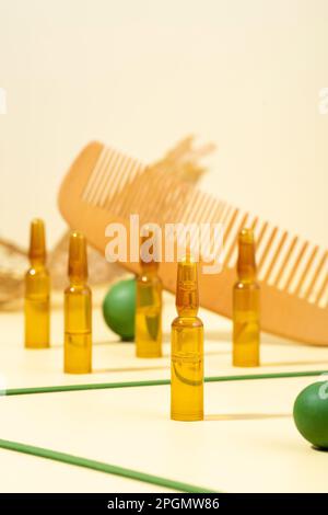 Fotografia moderna e creativa. Ampolle cosmetiche con siero per la crescita dei capelli, restauro.pettine, puntine verdi su sfondo beige.concetto di bellezza h Foto Stock