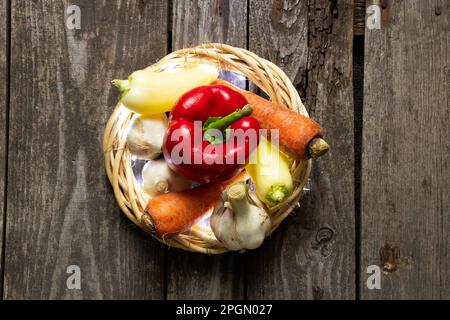 pepe carote aglio dall'orto giacciono su un vecchio tavolo di legno Foto Stock