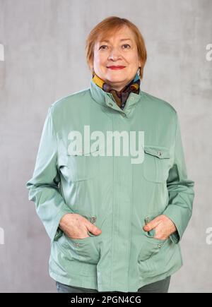 Donna anziana in piedi con fiducia vestita con abiti caldi con un sorriso pieno di allegria Foto Stock