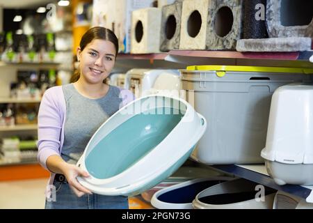 Donna gatto proprietario scelta vassoio di plastica lettiera in negozio di animali domestici Foto Stock