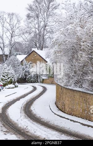 Una strada coperta di neve a Baildon, Yorkshire. Le auto hanno percorso la neve lasciando i segni degli pneumatici. Foto Stock