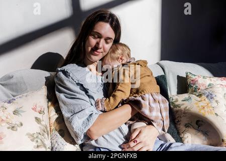 Madre con bambina che si rilassa sul divano a casa Foto Stock