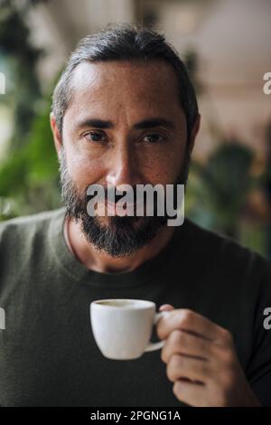 Uomo sorridente che tiene una tazza di caffè Foto Stock