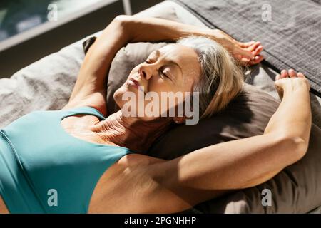 Donna matura che fa yoga a letto Foto Stock