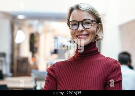 Donna d'affari felice che indossa gli occhiali in ufficio Foto Stock