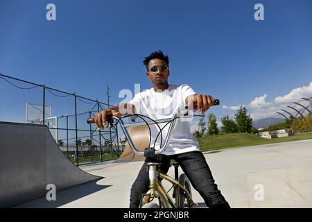 Giovane uomo seduto su una bicicletta BMX Foto Stock