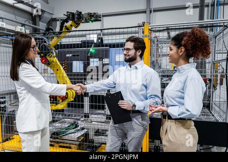 Felice uomo d'affari che scuote le mani con la donna d'affari da un collega in fabbrica Foto Stock