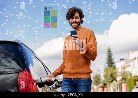 Giovane uomo felice che usa lo smartphone per ricaricare l'auto elettrica Foto Stock