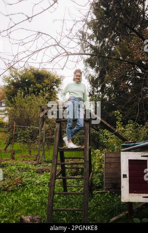 Donna sorridente in piedi su una scala di legno Foto Stock