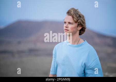 Giovane uomo contemplativo che indossa una t-shirt blu Foto Stock