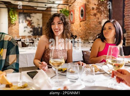 Donne felici che si godono la cena con gli amici al ristorante Foto Stock