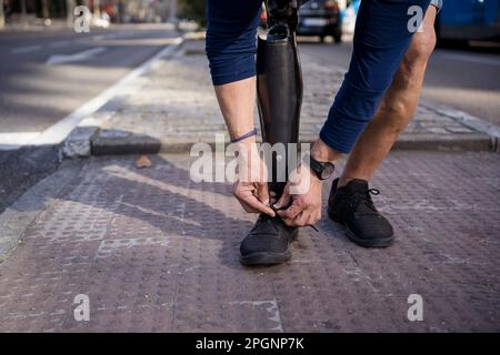 Uomo con gamba amputata che legano la scarpa sul sentiero Foto Stock