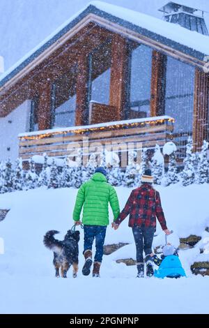 Genitori con figlio e cane che camminano nella neve Foto Stock