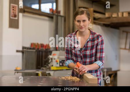 Giovane artigiano che lavora in bottega del legno Foto Stock