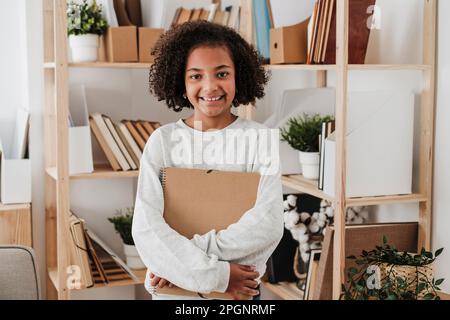 Ragazza sorridente che tiene a casa un notebook a spirale Foto Stock
