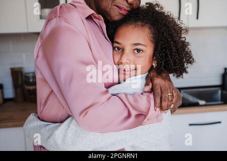 Nonna abbracciando la nonna in cucina a casa Foto Stock